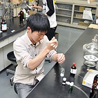 <span class="qrinews-figure-title">2014年11月11日 修士2年の酒谷さん</span>　ポルフィリンとキノイドポルフィリンの連結分子を研究しています。（撮影場所：<a href="http://www.cm.kyushu-u.ac.jp/wshinmyo/" target="_blank">構造有機化学研究室</a>）