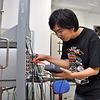 <span class="qrinews-figure-title">2012年8月14日 学部4年の富田さん</span>　ミュー粒子から電子への崩壊過程の寿命測定を行なっています。（撮影場所：<a href="http://epp.phys.kyushu-u.ac.jp/" target="_blank">素粒子実験研究室</a>）