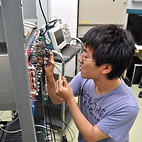 <span class="qrinews-figure-title">2012年9月24日 学部4年の中居さん</span>　ミュー粒子から電子への崩壊過程の寿命測定を行なっています。（撮影場所：<a href="http://epp.phys.kyushu-u.ac.jp/" target="_blank">素粒子実験研究室</a>）