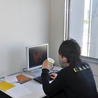 <span class="qrinews-figure-title">2013年12月16日 学部4年の富田さん</span>　楕円体粒子のガラス転移のシュミレーションをしています。（撮影場所：<a href="http://www.cmt.phys.kyushu-u.ac.jp/" target="_blank">物性理論研究室</a>）