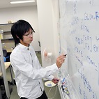 <span class="qrinews-figure-title">2014年1月16日 修士1年の赤峰さん</span>　体積が最小となる多様体を研究しています。（撮影場所：<a href="http://www.math.kyushu-u.ac.jp" target="_blank">数理学研究教育棟 院生室4</a>）
