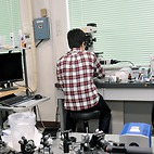 <span class="qrinews-figure-title">2014年5月13日 修士1年の栗原さん</span>　ビデオマイクロレオロジーを用いて微生物の懸濁液中におけるコロイド粒子の揺らぎを研究しています。無生物粒子の液体中とは異なる挙動を調べています。（撮影場所：<a href="http://sleipnir.sci.kyushu-u.ac.jp/mizuno/" target="_blank">複雑物性基礎研究室</a>）