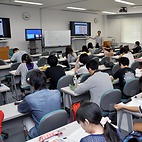 <span class="qrinews-figure-title">2014年6月26日 生物学科の講義風景</span>　今日の写真は生物学科学部3年生用の講義の様子です。伊藤先生の分子神経生物学の講義です。遠隔講義システムを利用して伊都地区からも受講できるようになっていました。（撮影場所：<a href="https://maps.google.co.jp/maps?q=33.626591,130.425364+(here)&z=18" target="_blank">シス生セミナー1，2</a>）