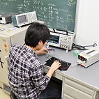 <span class="qrinews-figure-title">2014年9月22日 修士2年の中居さん</span>　COMET実験におけるトリガー検出器を開発しています。ミューオンが電子に転換する事象を探す為の、記録するデータを選別する検出器です。（撮影場所：<a href="http://epp.phys.kyushu-u.ac.jp" target="_blank">素粒子実験研究室</a>）