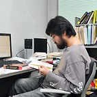 <span class="qrinews-figure-title">2014年12月22日 特別研究員の久保さん</span>　曲がった軸上における場の理論を研究しています。等加速度運動している人からは周りが温度をもつように見えるというUnruh効果を足がかりにして解き明かしていきたいです。（撮影場所：<a href="http://higgs.phys.kyushu-u.ac.jp" target="_blank">素粒子理論研究室</a>）