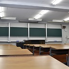 <span class="qrinews-figure-title">2015年3月23日 講義室（物理）</span>　物理学科の講義室です。時折上空を通る飛行機の轟音との戦い場所。この時期は大学入試の為に綺麗になっていますが、後ろ側の黒板には適当な落書きをよく見かけました。（撮影場所：<a href="https://maps.google.co.jp/maps?q=33.625619,130.425858+(here)&z=18" target="_blank">物理第1講義室</a>）