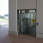 <span class="qrinews-figure-title">2015年8月5日 伊都の理学部に入館</span>　センターゾーンから見て理学部の建物正面左手にあるエレベーターの部屋に入り、1階で上履に履き替えます。3階にある受付で、学生証や鍵貸出用の物を提示すると建物に入れます。受付で渡される入場許可証を首から下げておきましょう。（撮影場所：<a href="https://maps.google.co.jp/maps?q=33.596433,130.221506" target="_blank">伊都キャンパス</a>）