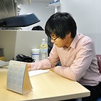 <span class="qrinews-figure-title">2016年1月18日 博士1年の李さん</span>　力学系の中でランダムな現象が起こっている条件を研究しています。量子力学でのランダムネスや誤差について組み合わせやフーリエ解析を用いて詳しく調べています。（撮影場所：<a href="http://www.math.kyushu-u.ac.jp" target="_blank">数理学府_院生室</a>）